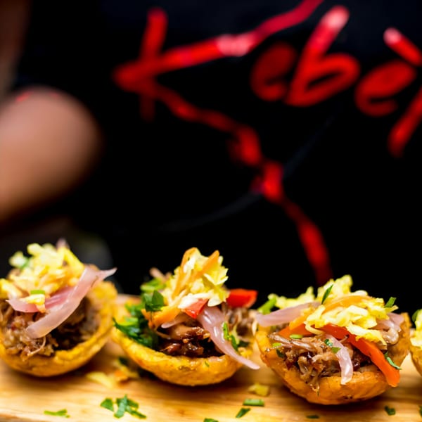 Close-up of Haitian plantain cups filled with shredded meat, pickled onions, and vegetables.
